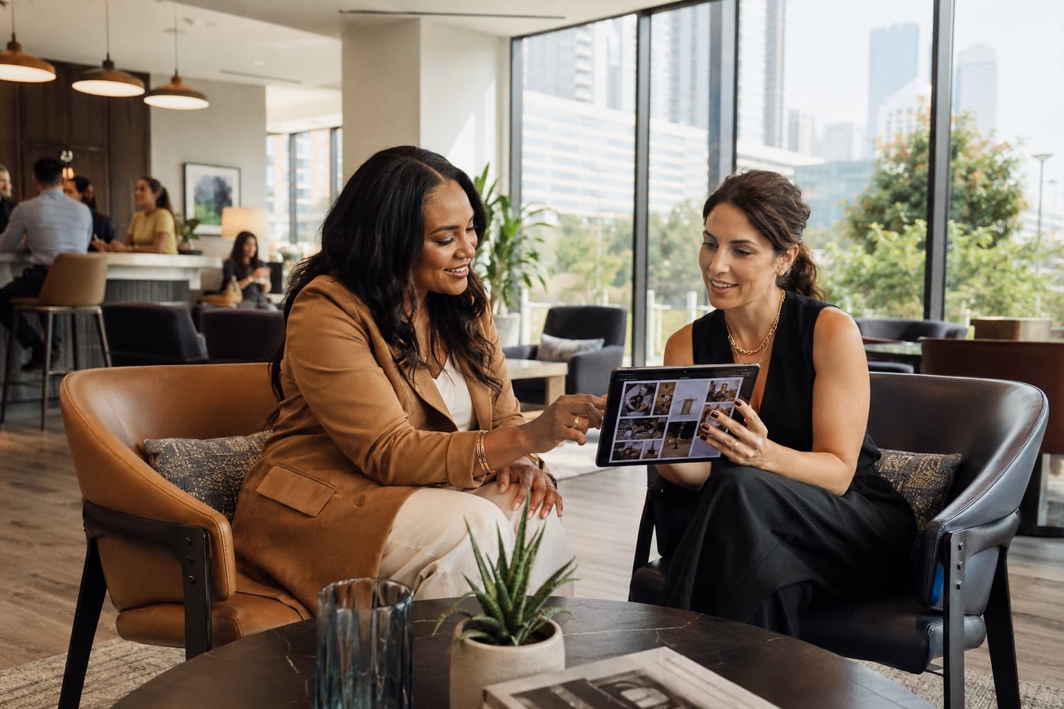A Le Château Hospitality representative and a community manager reviewing programming options together on a tablet in an apartment lounge.